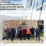 Grafik zur Klausurtagung 2025 des Sächsischen Baugewerbeverbandes im Solar-Appartement-Resort „Summit of Saxony“: Im oberen Teil steht der Veranstaltungstitel vor der Fassade eines solarthermisch aktiven Gebäudes, darunter posiert eine Gruppe von Teilnehmenden vor dem hölzernen Empfangsgebäude mit buntem „Reception“-Schriftzug.